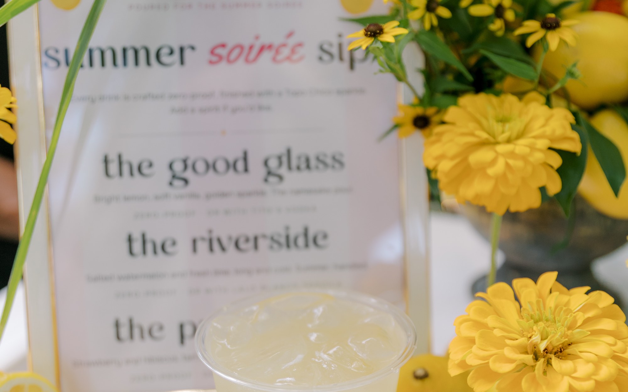 A summer soirée sips menu sign with a citrus pour and fresh lemons