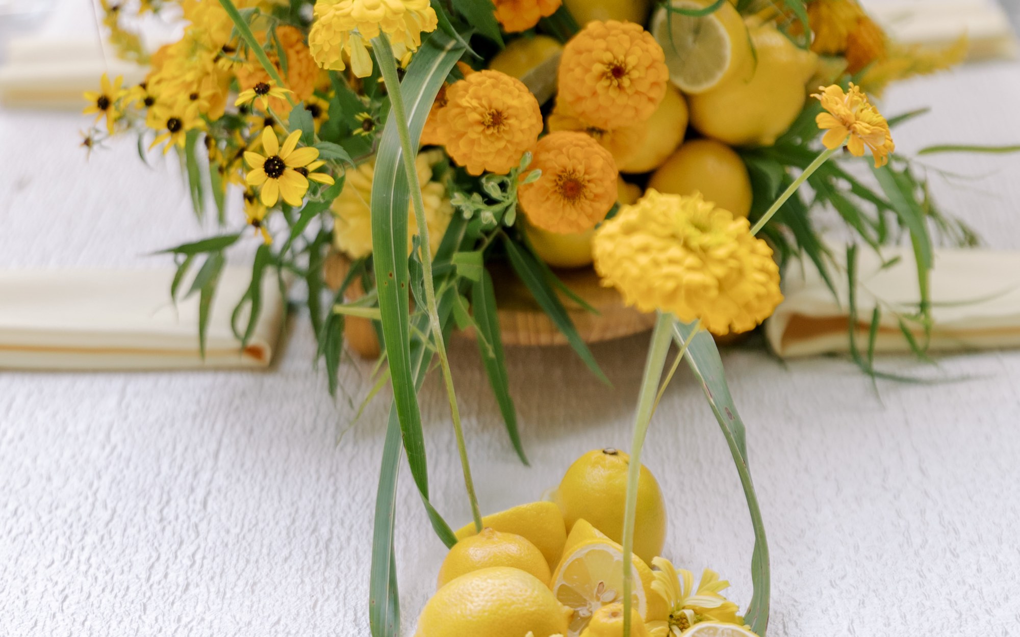A yellow floral centerpiece with fresh lemons on a styled table